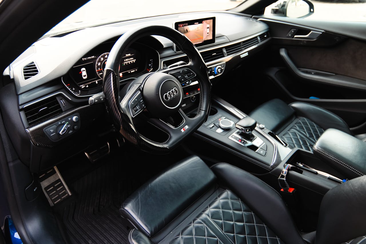 Home Sleek interior view of a luxury car featuring black leather seats, steering wheel, and advanced dashboard.